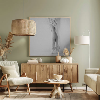 A framed, grainy black and white photograph of a dancer's legs and feet. The dancer stands on tiptoes against a white wall, wearing a delicate lace skirt. Poster