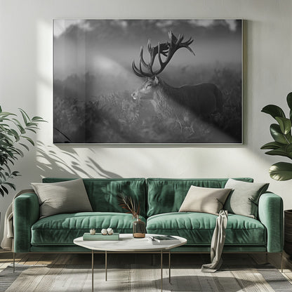 A majestic stag with large antlers is captured in a black and white photograph, standing in a field of ferns with a foggy forest in the background. The image has a moody and atmospheric quality and is displayed within a silver frame. Poster