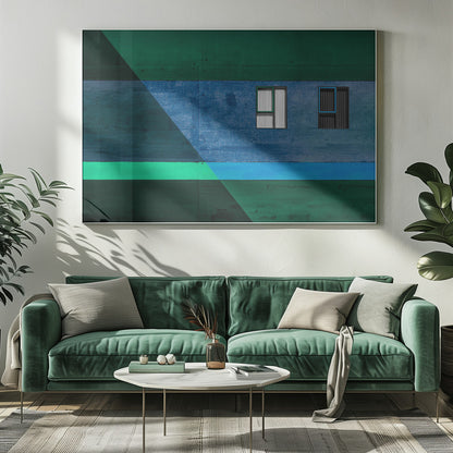 A framed abstract architectural photograph featuring a color-blocked facade. A central horizontal band of textured blue wall contains two small, distinct windows. This is flanked by upper and lower sections of dark green. A large, dark diagonal shape overlays the left side of the composition, creating sharp geometric lines. Decor