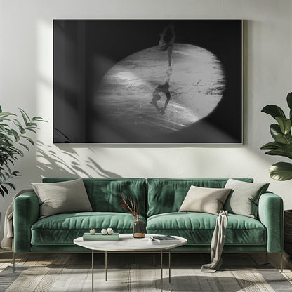 A dramatic black and white framed photograph of a female figure skater performing on ice. She is illuminated by a single spotlight, holding a graceful standing split pose, with her reflection visible on the ice below. Poster