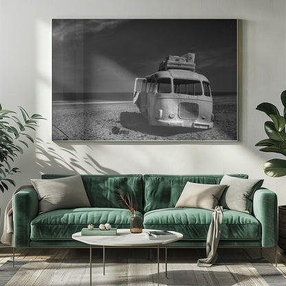 A dramatic black and white photograph of a vintage bus with luggage stacked on the roof, parked on a sandy beach. The ocean stretches out to the horizon under a dark, moody sky, with a small flock of birds flying in the distance. Print