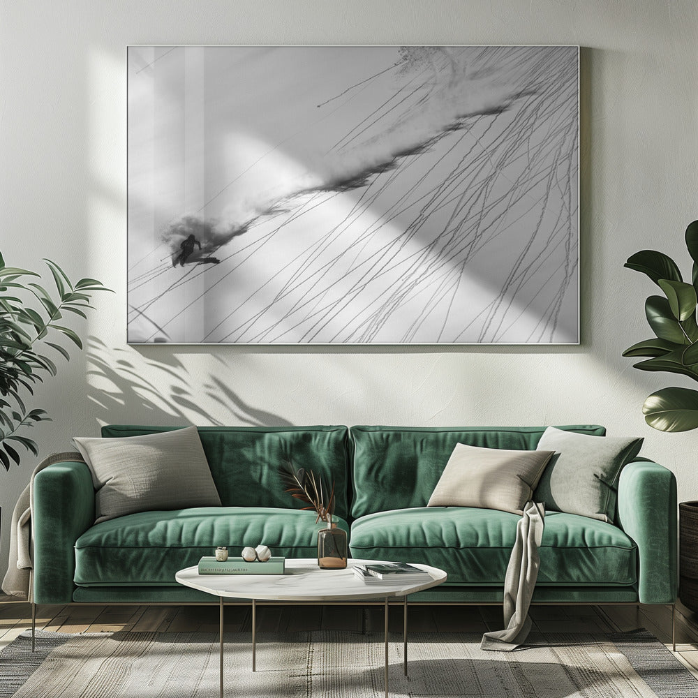 A dramatic black and white overhead photograph of a skier carving down a steep, powder-filled mountain slope, kicking up a huge plume of snow. Numerous ski tracks crisscross the pristine white snow, creating a pattern of dark lines. Poster