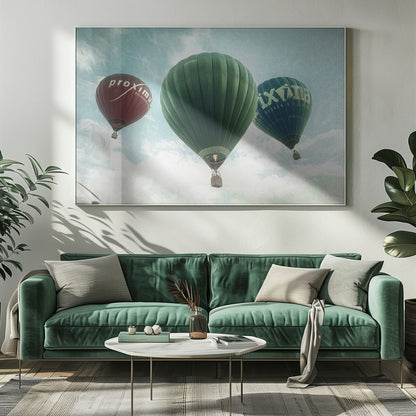 A low-angle photograph of three colorful hot air balloons floating in a cloudy blue sky, presented in a silver frame. A large green balloon is in the center, with a red balloon on the left and a dark blue balloon on the right, all featuring logos. Wall Art