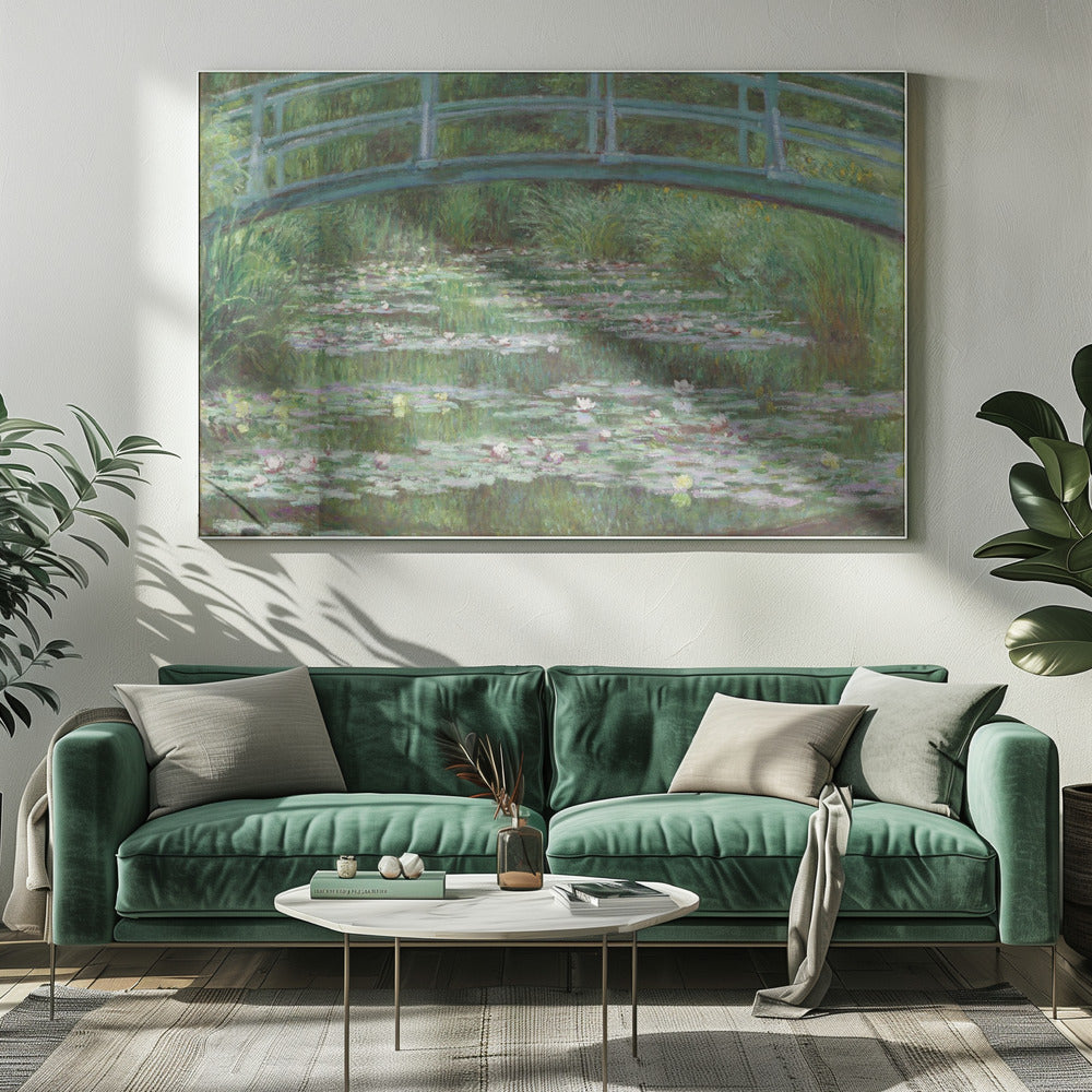 An Impressionist painting by Claude Monet depicting a green Japanese-style footbridge arching over a tranquil pond filled with blooming water lilies and lily pads, all rendered in soft, dappled brushstrokes and framed in a modern silver frame. Print