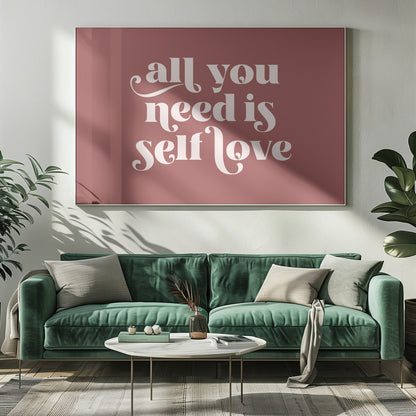 A framed art print with a dusty rose background. In the center, the phrase 'all you need is self love' is written in a creamy white, stylized, retro font. The artwork is enclosed in a simple silver frame. Decor