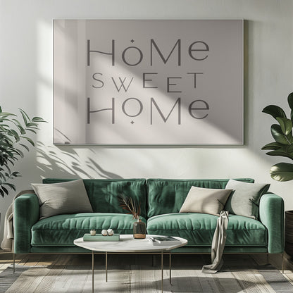 A minimalist wall art piece with the words 'Home Sweet Home' in a dark gray, stylized sans-serif font against a light beige background, all housed within a simple silver frame. Decor