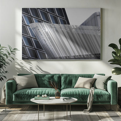 An abstract architectural photograph, framed in silver, showing a dynamic contrast between two modern building facades. In the background, a dark building features a grid of diamond-shaped windows with white frames, while a structure in the foreground creates a wave of fine, parallel white vertical lines against the sky and the other building. Print