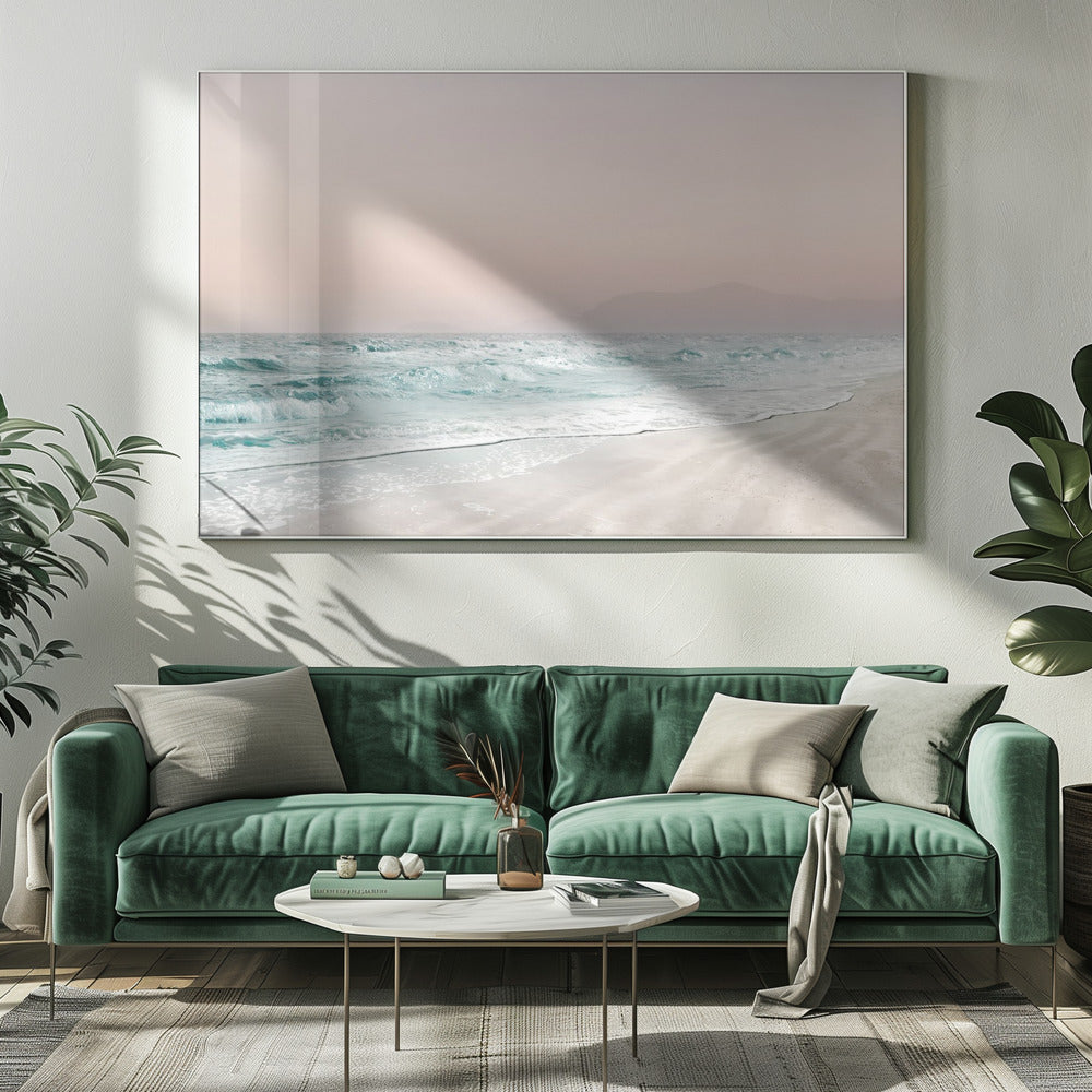 A serene coastal scene with gentle turquoise waves washing onto a sandy beach. The sky is a soft, hazy pink, and faint outlines of mountains are visible in the distant background. The artwork is presented in a silver frame. Print