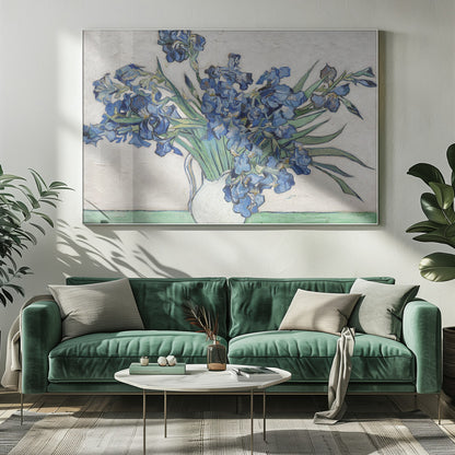 A framed print of Vincent van Gogh's famous painting 'Irises'. It features a large bouquet of vibrant blue iris flowers with long green leaves, arranged in a simple white pitcher. The background is a textured off-white wall, and the pitcher rests on a light green surface. The painting is in the post-impressionist style with thick, visible brushstrokes. Wall Art