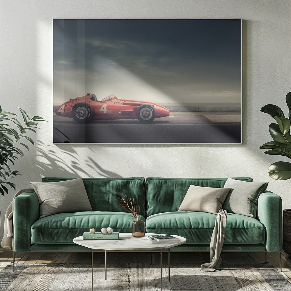 A side profile of a vintage red single-seater race car with the number 4 painted on it, parked on a seaside road under a dramatic, cloudy sky. The image has a muted, nostalgic color palette and is shown within a silver frame. Decor