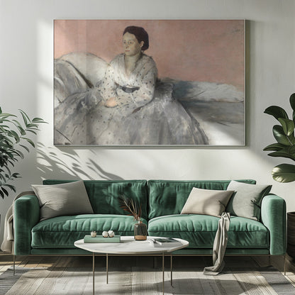 A framed impressionist painting titled 'Mélancolie' by Edgar Degas, depicting a woman with dark hair pulled back, seated on a couch or bed. She wears a white and grey polka-dotted dress with a black sash and has a pensive expression, looking off to the side against a soft pink background. Decor