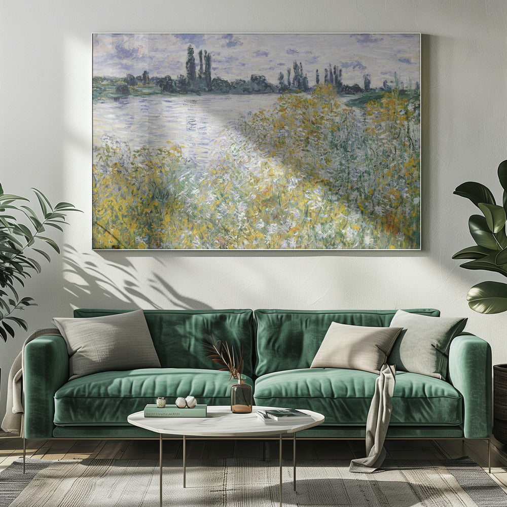 An impressionist landscape painting of a riverbank covered in yellow and white wildflowers. A calm river reflects the cloudy sky, and the opposite bank is lined with tall, dark poplar trees. The artwork is displayed in a silver frame. Artwork