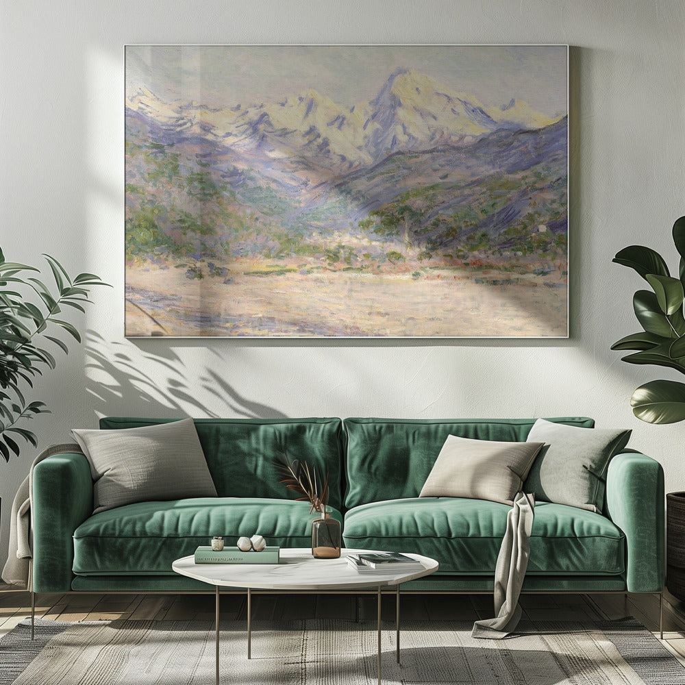 An impressionistic painting of a vast mountain range. The snow-covered peaks are bathed in pale yellow sunlight, while the lower slopes are cast in shades of purple and blue. A wide, beige valley with patches of green foliage sits in the foreground, all rendered with visible, textured brushstrokes and displayed in a silver frame. Print