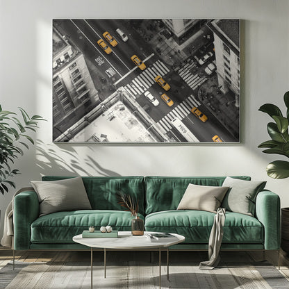 An aerial, black and white photograph of a bustling New York City intersection, with the iconic yellow taxi cabs highlighted in a vibrant selective color. Pedestrians cross the street as cars and a bus navigate the busy roads between tall buildings. Wall Art