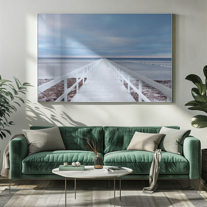A framed photograph capturing a long, white wooden pier from a central perspective, leading the eye across a calm, icy sea towards the distant horizon under a cloudy blue sky. Print