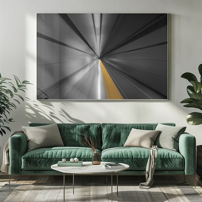 An abstract, long-exposure photograph from a first-person perspective inside a tunnel, creating a motion-blurred effect. The scene is mostly black and white, with lines radiating from a central vanishing point, but a single, bold yellow line runs down the center, adding a pop of selective color. The artwork is presented in a silver frame. Print