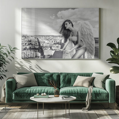 A framed black and white photograph of a woman with large angel wings wearing white lingerie, looking out over a cityscape from a high vantage point. Her long dark hair is blowing in the wind, and the sky is filled with clouds. Poster