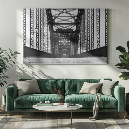 A framed, black and white, low-angle photograph capturing the symmetrical and intricate steel truss structure of a long bridge, creating a powerful vanishing point perspective down the center of the road. Poster