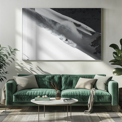 A dramatic black and white photograph of a skier speeding down a steep, snow-covered mountain, kicking up a large cloud of powder. The image is framed with a brushed silver border. Decor