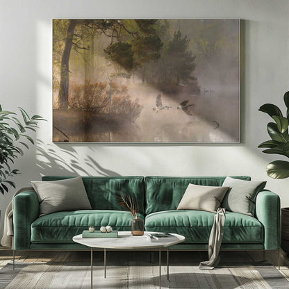 Two geese flying low over a misty forest lake at dawn, a serene nature photograph.