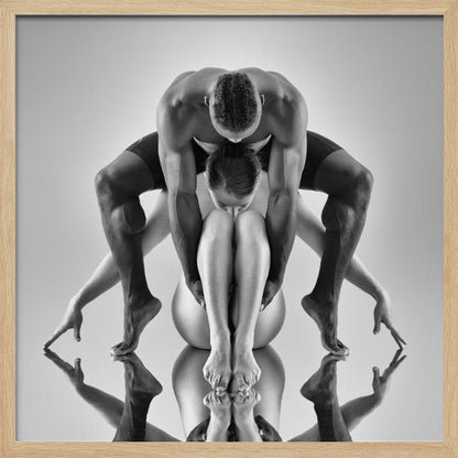 A framed black and white studio photograph of two dancers, a man and a woman, creating a symmetrical pose. The muscular man is positioned over the woman who is curled up beneath him. Their limbs are extended and reflected on the mirrored surface below, forming an abstract and powerful composition. Decor