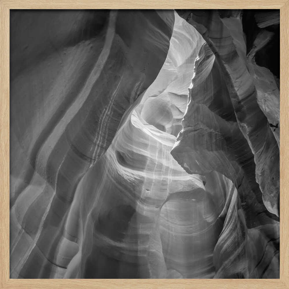 Black and white photo of light in a narrow slot canyon, highlighting smooth, layered rock formations. Nature wall art.