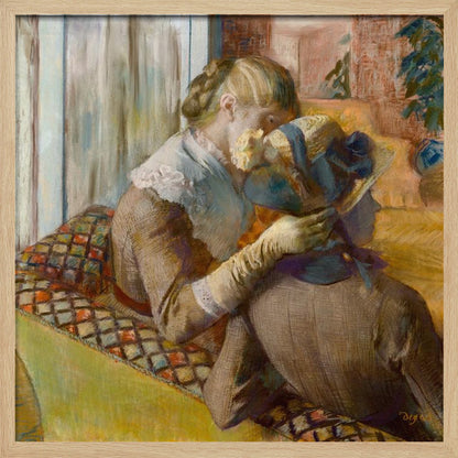 A framed Impressionist painting by Edgar Degas depicting two women. One woman, with blonde hair tied back, adjusts a hat with a blue ribbon on the other woman who is sitting with her back mostly to the viewer on a colorful patterned sofa. Print