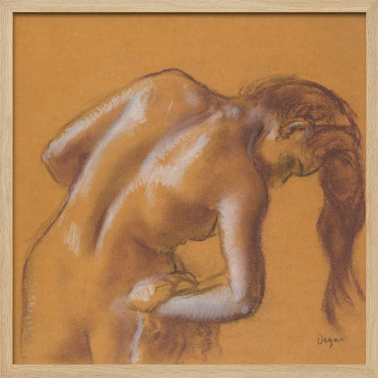 A framed pastel sketch by Edgar Degas titled 'After the Bath, Woman Drying Herself'. The artwork depicts a nude woman from the back, bending forward as if drying herself. The drawing is on a warm ochre-colored paper, with her form defined by brown lines and white highlights, especially along her spine and shoulders. Her long brown hair cascades down on the right side. Wall Art