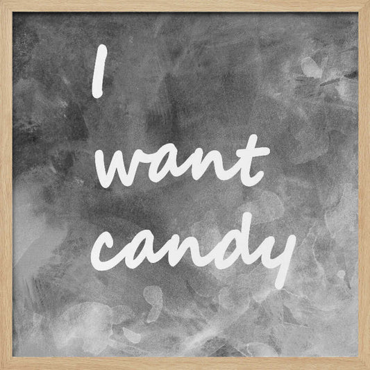 A framed typography art piece with a light brown wood frame. It features the phrase 'I want candy' in a white, handwritten script against a textured, dark gray and white chalkboard-style background. Wall Art