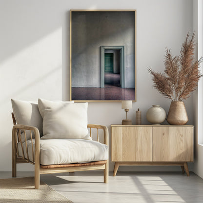 A minimalist photograph of a room with grey, textured walls and a reddish-brown floor, focusing on an open, light green doorway that reveals another room with a closed, darker green door, creating a sense of depth and perspective. Wall Art