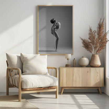 A framed black and white photograph of a graceful female dancer arching her back dramatically. She holds a long white elastic band that stretches down her body to her foot, emphasizing her athletic form and flexibility against a plain studio background. Print