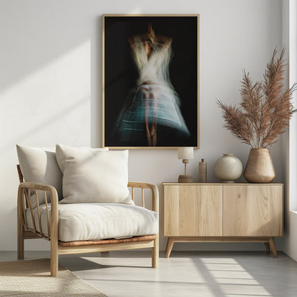 An ethereal, long-exposure photograph of a dancing figure against a dark gray background. The motion blur creates a ghostly effect, with white, gauzy fabric swirling around the upper body. The figure wears a transparent crinoline hoop skirt, revealing her legs and feet. Artwork