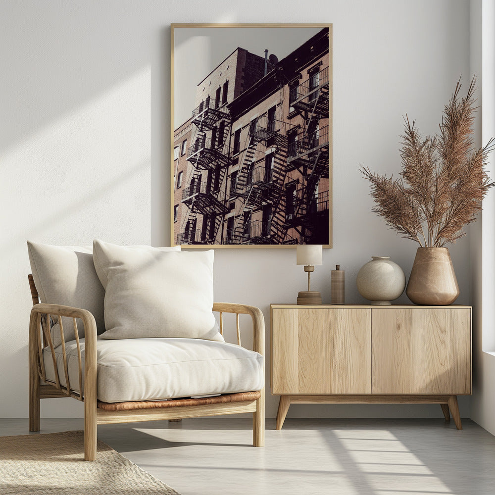 A low-angle photograph of a classic brick apartment building, with a complex pattern of black metal fire escapes casting long, dramatic shadows across the sunlit facade against a pale sky. Decor