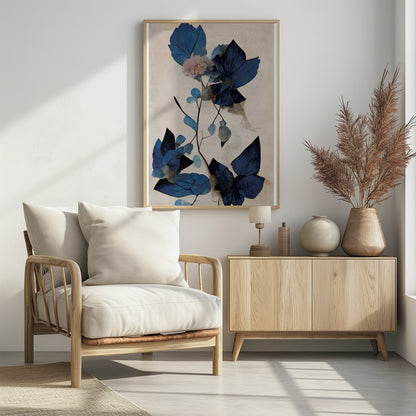An abstract botanical artwork featuring large, angular leaves in various shades of deep and light blue. A single delicate pink flower blooms on a thin, dark stem against a textured, light cream background. The piece is displayed in a thin black frame. Artwork