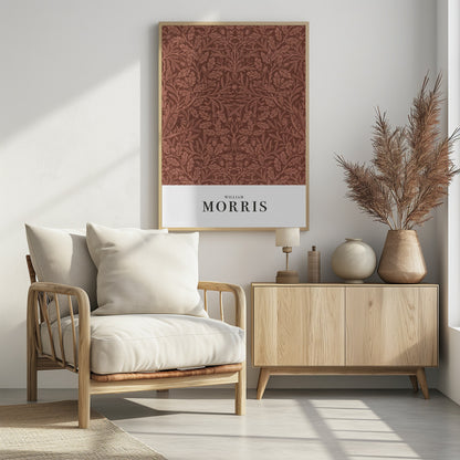A framed art print of a classic William Morris design. The intricate, symmetrical pattern features terracotta-colored oak leaves, acorns, and stylized flowers on a rich brown background. Below the pattern is a white section with the name 'WILLIAM MORRIS' in black serif font. Print