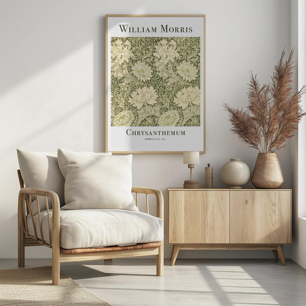 A framed art print of William Morris's 'Chrysanthemum' pattern from 1877. The design features a dense, repeating pattern of large, cream-colored chrysanthemums and foliage in shades of sage green on a dark green background. The poster has a white border with the artist's name at the top and the title at the bottom. Print