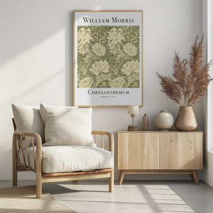 A framed art print of William Morris's 'Chrysanthemum' pattern from 1877. The design features a dense, repeating pattern of large, cream-colored chrysanthemums and foliage in shades of sage green on a dark green background. The poster has a white border with the artist's name at the top and the title at the bottom. Print