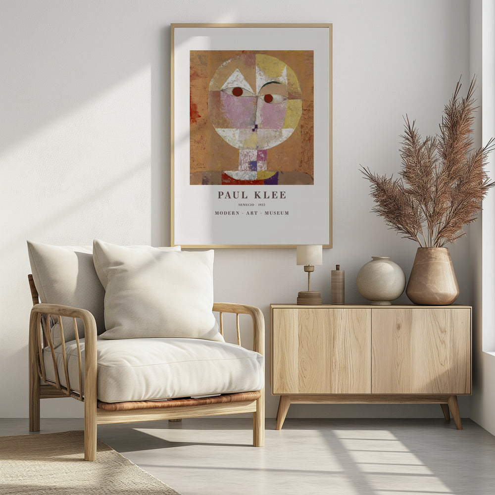 A framed museum poster of Paul Klee's 1922 painting 'Senecio'. The artwork is an abstract, geometric portrait of a human head in warm tones of orange, yellow, pink, and red against a textured brown background. The text 'PAUL KLEE', 'SENECIO - 1922', and 'MODERN - ART - MUSEUM' is printed below the image. Print