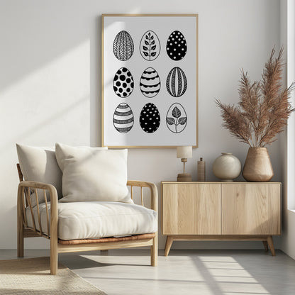 A black and white art print featuring a 3x3 grid of nine illustrated Easter eggs. Each egg has a unique, hand-drawn pattern, including polka dots, stripes, chevrons, florals, and leafy branches, all within a thin black frame. Poster