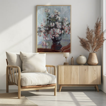 An impressionist painting by Claude Monet depicting a large bouquet of white and pink chrysanthemums in a dark, ornate vase. The vase sits on a reflective, reddish-brown wooden table, and the background is a textured light blue wall. The painting is framed in black. Artwork