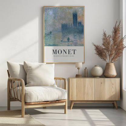 A framed art poster of Claude Monet's impressionist painting, 'The Houses of Parliament'. The painting shows the silhouette of the building through a dense fog over the River Thames, rendered in soft blues, greys, and muted oranges. The artwork is set above a wide, off-white border with the text 'MONET' and 'THE HOUSES OF PARLIAMENT 1903-1904'. Poster