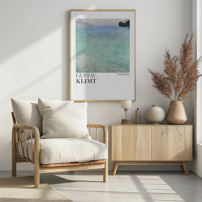 A poster of Gustav Klimt's painting 'Attersee', featuring a tranquil, impressionistic view of a lake with shimmering turquoise and green water under a muted blue and gray sky. The artwork is presented in a modern format with the artist's name and the painting's title below, all within a thin black frame. Poster