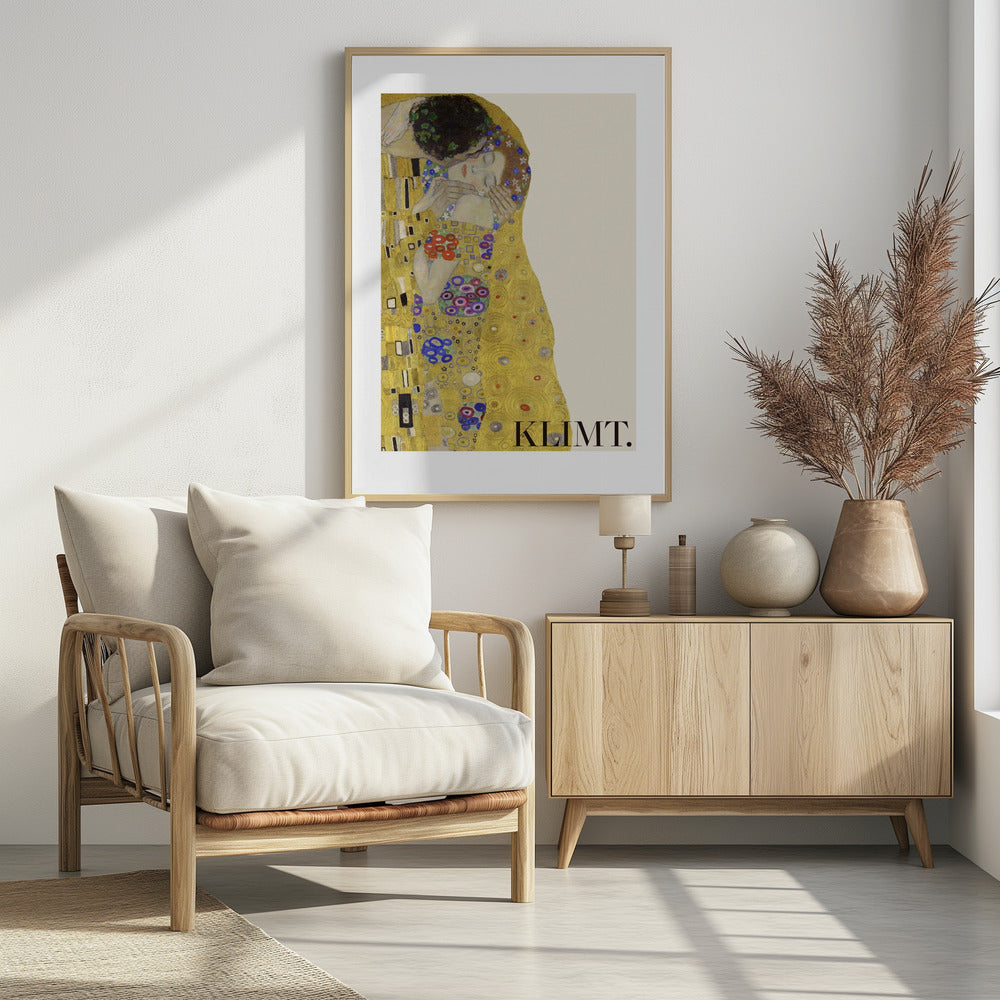 A framed art print of Gustav Klimt's 'The Kiss'. A couple embraces in ornate golden robes against a shimmering gold background. The poster includes the artist's name 'KLIMT.' in the lower right. Decor