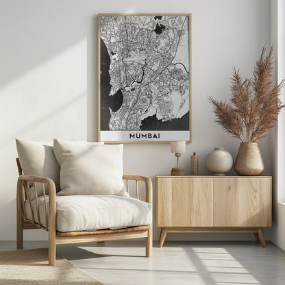 A minimalist black and white framed map of Mumbai. The city's intricate road network is depicted in black lines on a white background, with surrounding water bodies shown in a textured dark grey. The name 'MUMBAI' is in bold, uppercase letters at the bottom. Print