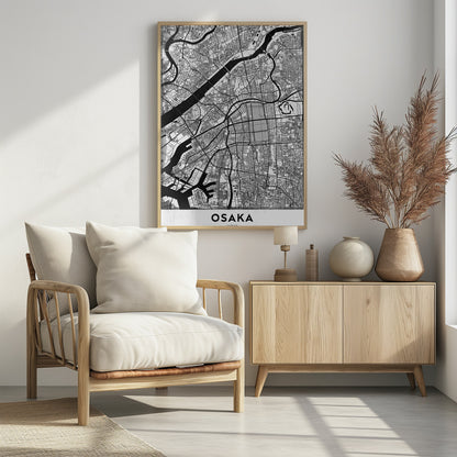 A framed black and white map of Osaka, Japan. The map details the city's streets, blocks, and rivers in a modern, graphic style. At the bottom, a white border contains the word 'OSAKA' in a bold, black, sans-serif font. Print