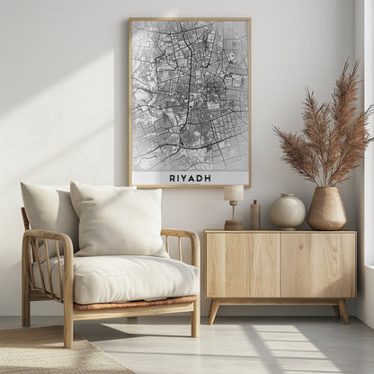 A minimalist, black and white framed poster of a city map of Riyadh. The map details the intricate network of streets and city blocks in black lines on a textured, light gray background. At the bottom, the word 'RIYADH' is printed in a bold, black, sans-serif font. Wall Art