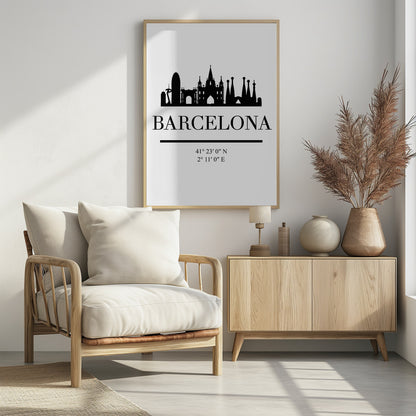 A minimalist black and white poster of Barcelona, Spain. It features a black silhouette of the city's skyline, including the Sagrada Familia, above the word 'BARCELONA' in a large serif font. Below the city name are its geographical coordinates, all set against a clean white background and framed in black. Print