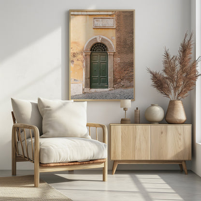 A vertical shot of a rustic European street scene featuring a dark green arched wooden door set into a stone frame. The building's facade is a mix of peeling yellow ochre plaster and exposed red brick. Above the door is a marble plaque that reads 'SALITA RI DEL GRILLO', and the ground is paved with grey cobblestones. Wall Art