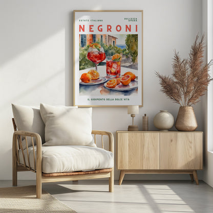 A vintage-style poster for a Negroni cocktail with the words 'Estate Italiana' and 'Negroni' at the top. The poster features a watercolor illustration of two glasses of Negroni on a white table with fresh oranges, set against a sunny Italian coastal backdrop with a villa and the sea. At the bottom, it reads 'Il Godimento Della Dolce Vita'. Artwork