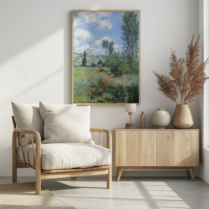 An impressionist painting depicting a vibrant green field filled with red poppies under a bright blue sky with fluffy white clouds. Tall green trees stand on the right, and in the distance, a small village with a church steeple is nestled in the rolling hills. Decor